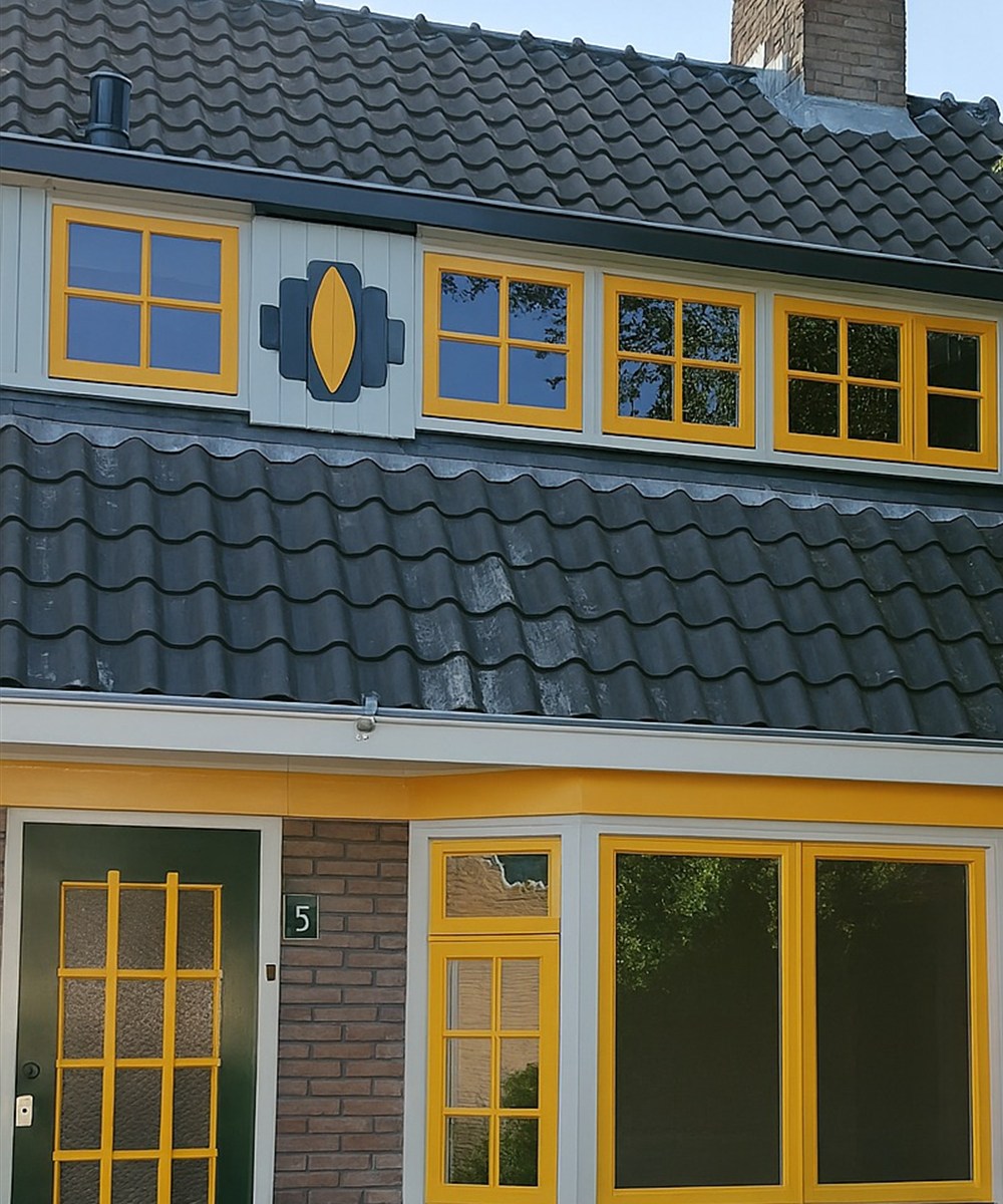 Gerestaureerde gevel in Delft door SRBBOUW B.V.: gele houten kozijnen, dakkapel en groene voordeur