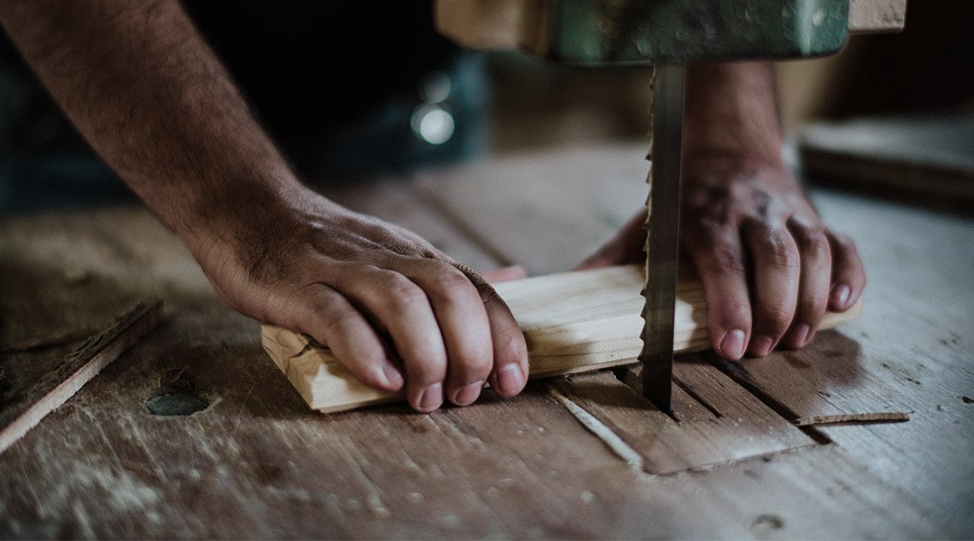Vakman zaagt hout op maat met een lintzaag tijdens een verbouwing